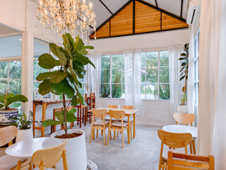 ** Bright and Airy Modern Cafe Interior with Wooden Furniture and Lush Greenery in a Sunlit Room..**