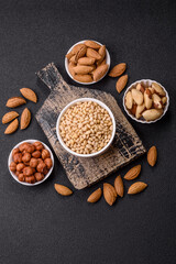 Peeled pine nuts in a bowl on a dark concrete background