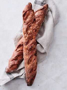 Warm, crusty loaves of artisan bread lie gracefully on a plush linen, capturing the essence of homemade baking. Perfect for any meal, they beckon with their golden exterior and inviting smell