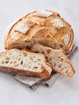 Golden crusted artisan bread sits freshly baked on a simple linen cloth, with a few slices revealing its soft, airy interior. The inviting aroma beckons for a taste during a cozy afternoon