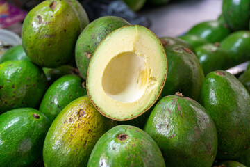 A vibrant collection of fresh green avocados neatly arranged in a market display. Each avocado showcases its smooth, unblemished skin, reflecting a rich green hue.