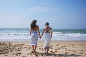 Two women walking hand in hand on beach