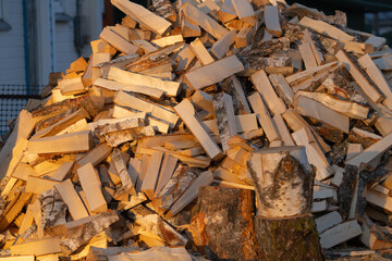 Chopped birch firewood on the street in the village next to a wooden house