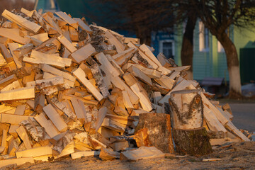 Chopped birch firewood on the street in the village next to a wooden house