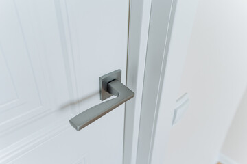A CloseUp View of a Contemporary Modern Door Handle Installed on a White Painted Door, Set Against a Bright Interior Environment, Showcasing Its Elegance and Design Features
