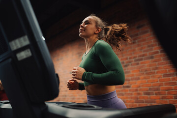 Determined sportswoman running on treadmill in modern gym