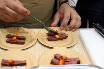 chef preparando un aperitivo de carne con frutos rojos con sus manos y una cuchara
