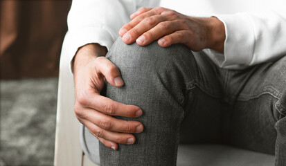 Man suffering from knee pain at home, closeup