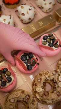 Assorted gourmet pastries in vibrant colors, decorated with berries, nuts and gold bars, on display