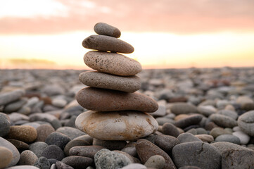Tower of flat stones on beach. Balancing stones one on another on seashore at sunset, close-up. Pyramid of stones. LATZA. Concept of relaxation, serenity, place of power, meditations.
