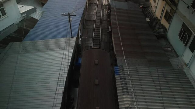 Train passing through Maeklong Railway Market in Thailand, squeezing between market stalls with goods just inches from the tracks