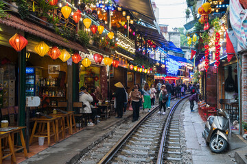 A vibrant street scene with railway tracks adorned with colorful lanterns enhancing community charm...