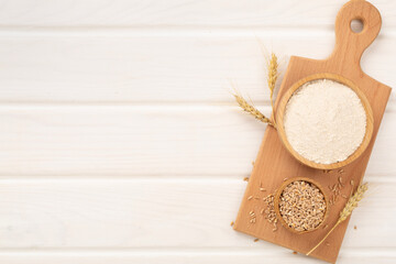 Bowl with spelt flour on wooden background, top view