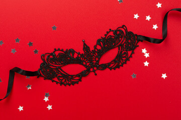 Bright carnival mask with confetti on color background, top view