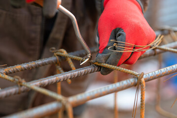 The hands of a male builder tie the reinforcement with a crochet. Close-up.  Reinforcement works....