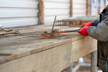 Close-up of a builder's hand bending rebar on a hand machine. Reinforcement works. Construction. 