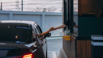 Young Man receiving coffee at drive thru counter., Drive thru and take away for protect covid19.