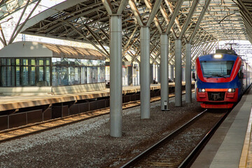 Naklejka premium Local train arrive to railway station platform in Russia. Train station. Modern railway transportation concept. Railroad. Commercial transport