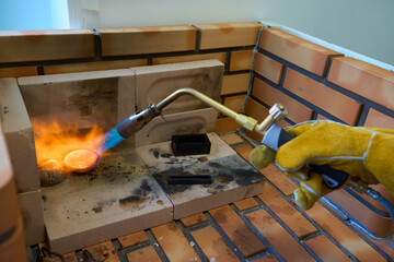 Jeweler melting gold with a gas welding torch in a small workshop
