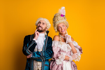 Couple in historical costumes posing against a vivid yellow background, elegantly dressed in a vintage style