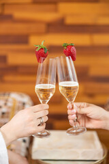 Two champagne glasses clink together, adorned with fresh strawberries, celebrating a moment of joy and indulgence.