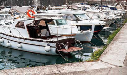 A collection of boats docked in a marina, showcasing various watercraft with protective fenders and...