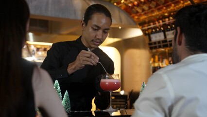 Focused on mixed punch cocktail Christmas theme garnishing with burning cinnamon and star anise by bartender, serving decorated green neon snow Christmas tree bar special cool drink luxury. Vinosity.