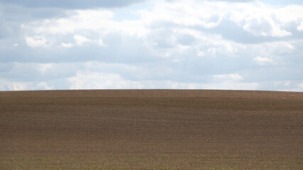 Schlichtes einfaches Landschaftsbild von einem Acker im Frühling bei bewölktem Wetter im...