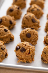 Chocolate chip cookies with pecan nuts, cookie dough ready on a baking sheet