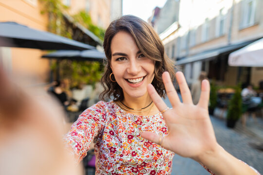 POV view of young woman blogger taking selfie on smartphone, communicating video call online with subscribers recording stories for social media vlog outdoors. Adult girl standing in urban city street