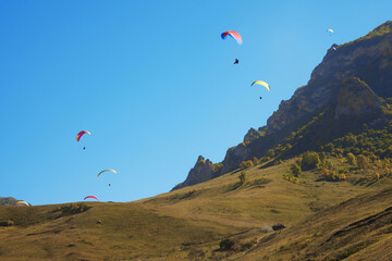 High-altitude paragliding. Many colorful paragliders in the sky on the picturesque background of a...