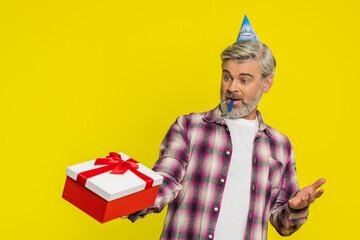 Mature man beams with delight receiving present gift box topped by vivid red ribbon, revealing...
