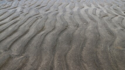 Beach sand texture with wavy pattern, natural background of small rippled sand
