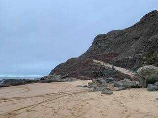 Scenic coastal cliff and sandy beach under overcast sky, perfect for summer getaway or coastal...