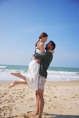 Smiling couple embracing on sandy beach during romantic summer vacation