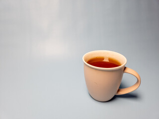 A glass of hot sweet tea isolated on a light blue background