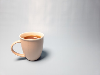 A glass of hot sweet tea isolated on a light blue background