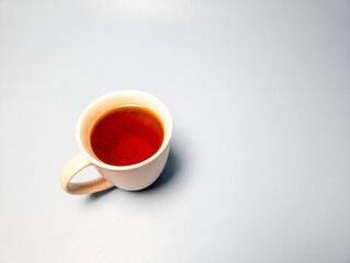 A glass of hot sweet tea isolated on a light blue background