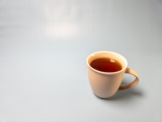 A glass of hot sweet tea isolated on a light blue background