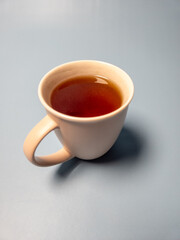A glass of hot sweet tea isolated on a light blue background