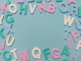 Multicolored eva foam letters scattered on blue background.