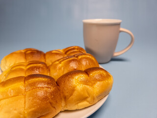 A plate of srikaya torn bread and a glass of sweet tea isolated on a light blue background
