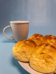A plate of srikaya torn bread and a glass of sweet tea isolated on a light blue background