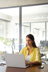 Focused young indian business woman, it specialist using laptop at work in office. Female freelance...