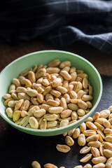 Roasted salted peanuts in bowl on wooden table.