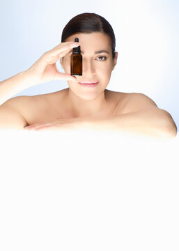 Beautiful natural woman holding skincare product bottle for beauty and skincare concept on a light background