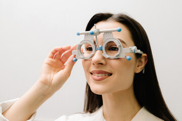 Girl is wearing trial frame glasses for eye exam vision test by ophthalmologist. Trial frame...
