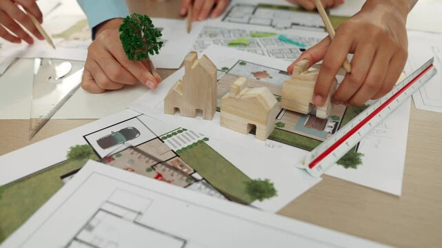 Architects determine position of tree or house using building blueprint on messy table with architectural project and measurement tool scattered around. Business and environment concept. Delineation.