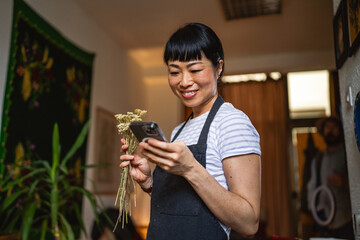 japanese woman use mobile phone while hold herbals at herbs workshop