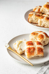 Traditional Easter hot cross buns on white plate with butter on white background isolated with text space. Delicious Easter breakfast